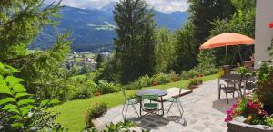 eine Terrasse mit Tisch und Stühlen und einem Sonnenschirm in der Unterkunft Comfort and Views in Hermagor