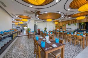 a restaurant with wooden tables and chairs and yellow lights at Fivitel Hoi An Hotel in Hoi An