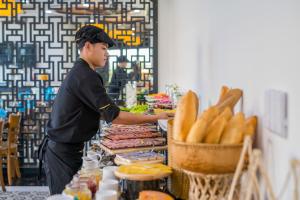 a man preparing food at a counter in a store at Fivitel Hoi An Hotel in Hoi An