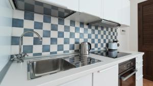 a kitchen with a stainless steel sink and blue and white tiles at Italianway - Ottoventi Apartments in Lampedusa