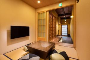uma sala de estar com um sofá e uma televisão em Tsumugi Horikawakichimonji em Quioto