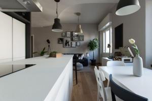 een keuken en een woonkamer met een witte bar en stoelen bij Calìxa in Cagliari