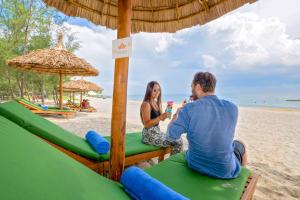 a man and a woman sitting on a table on the beach at Fivitel Hoi An Hotel in Hoi An