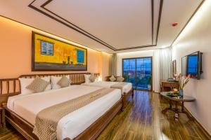 a hotel room with two beds and a window at Fivitel Hoi An Hotel in Hoi An