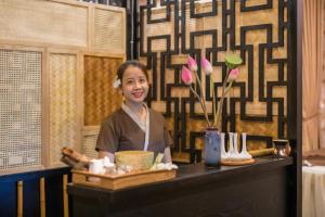 a woman standing behind a counter in a restaurant at Fivitel Hoi An Hotel in Hoi An