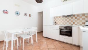 a kitchen with white cabinets and a table and chairs at Italianway - Ottoventi Apartments in Lampedusa