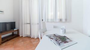 a white room with a television and a table with a magazine at Italianway - Ottoventi Apartments in Lampedusa