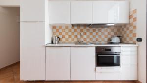 a white kitchen with white cabinets and a sink at Italianway - Ottoventi Apartments in Lampedusa