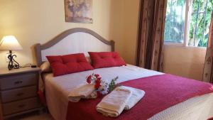 Un dormitorio con una cama con almohadas rojas y flores. en La Morera, El Palmar, en El Palmar