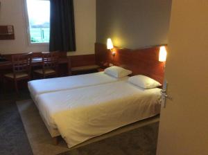 a bedroom with a large white bed and a table at Armony Hotel in Bourg-Achard