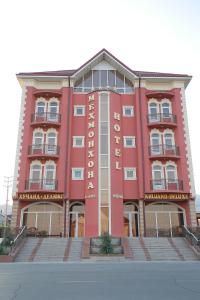 um edifício vermelho com uma placa na frente dele em Khujand Deluxe Hotel em Khujand