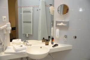 a white bathroom with a sink and a mirror at Warias Hotel & Restaurant am Geiseltalsee - Nähe Merseburg in Braunsbedra