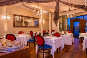 un comedor con mesas blancas y sillas rojas en Frédéric Carrion Hôtel et Spa, en Viré