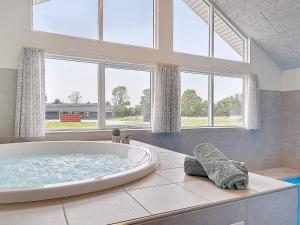 Cette chambre dispose d'une grande baignoire et de fenêtres. dans l'établissement 18 person holiday home in Grenaa, à Grenå