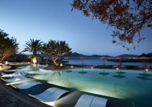 a swimming pool with lounge chairs at night at Porto Elounda Golf & Spa Resort, Six Senses Spa in Elounda