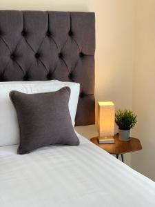 Cama con almohada gris y mesita de noche en Three Storey Townhouse with Parking en Telford