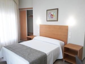 um quarto com uma cama branca e duas mesas em Hostal Montemayor em Moguer