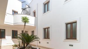 a white building with a palm tree in the courtyard at Italianway - Ottoventi Apartments in Lampedusa