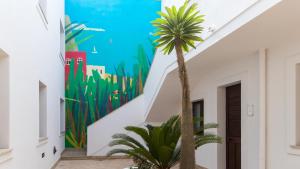 a palm tree in a hallway with a mural at Italianway - Ottoventi Apartments in Lampedusa