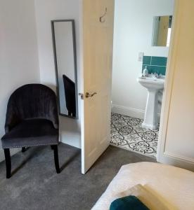 a bedroom with a chair and a sink and a mirror at Rosalind House in Carlisle