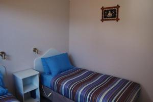 a bedroom with a blue and white bed and a blue wall at Strahan Bungalows in Strahan
