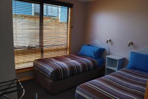 a bedroom with a bed and a window at Strahan Bungalows in Strahan