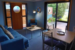 a living room with a blue couch and a table at Strahan Bungalows in Strahan