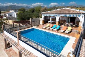 a swimming pool with chairs and a house at Villa Triana in Nerja