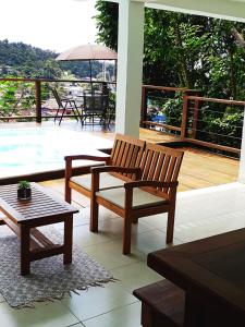 um pátio com dois bancos, uma mesa e uma piscina em SOL&MAR Suítes Ilhabela em Ilhabela