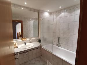 y baño con lavabo, bañera y espejo. en Haus Edelweiss, en Oberstdorf