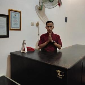 Un homme debout devant une table, les mains priant dans l'établissement Hotel Bundo Permai 1, à Pacitan