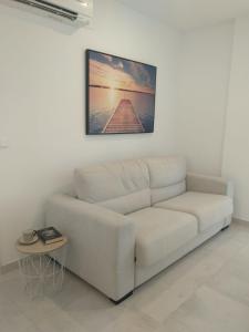 a white couch in a living room with a picture on the wall at TURISMO LOS LANCES TARIFA( PARKING GRATUITO) in Tarifa