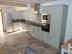 a kitchen with white cabinets and stainless steel appliances at Stable Cottage in Redlynch