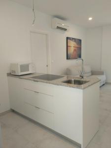 a white kitchen with a sink and a microwave at TURISMO LOS LANCES TARIFA( PARKING GRATUITO) in Tarifa