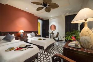 a hotel room with two beds and a table with a lamp at G Boutique Retreat Hoi An in Hoi An +49 photos