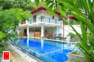 a villa with a swimming pool in front of a house at Villa Red Lobster in Hikkaduwa