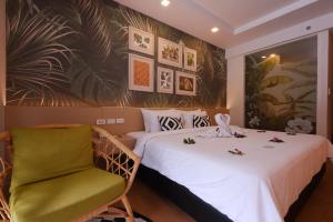 a hotel room with two beds and a green chair at Panan Krabi Resort - SHA Plus in Ao Nang Beach