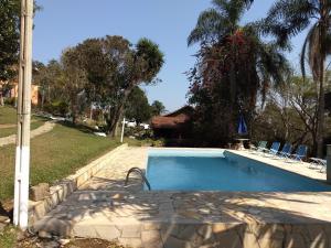 una piscina en un patio con sillas y árboles en Pousada Céu de Luz, en Itapeva