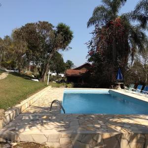 una piscina en un patio con sillas y árboles en Pousada Céu de Luz en Itapeva
