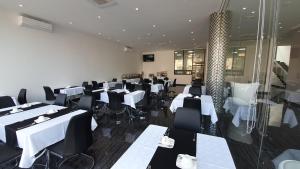 un comedor con mesas blancas y sillas negras en Indico Executivo Hotel, en Cidade de Nacala