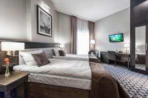 シュフィドニツァにあるRed Baron Hotel & Restaurantの大きなベッドとデスクが備わるホテルルームです。