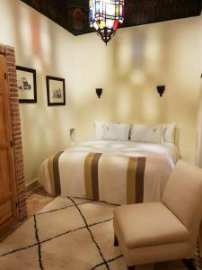 a bedroom with a bed with a chair and a window at Riad Les Trois Palmiers El Bacha in Marrakech