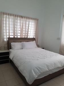 a bedroom with a bed with white sheets and a window at PINKY VILLA in Ipoh