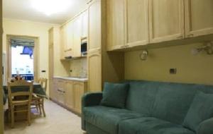 a living room with a blue couch and a kitchen at Baita Veglia in Livigno