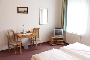 ein Hotelzimmer mit einem Tisch und einem TV in der Unterkunft Adler Hotel Dresden in Dresden