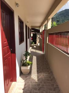 a hallway of a house with a red door and a plant at Recanto Lorenzi - Apartamentos in Ubatuba