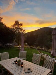 une table et des chaises en bois avec un coucher de soleil en arrière-plan dans l'établissement La Pierre d'Eau, à Fréland