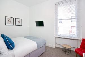 a bedroom with a bed and a red chair and a window at Interlude House B by City Living London in London