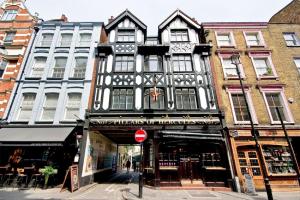倫敦的住宿－F3 Greek Street by City Living London，城市街道上的一座建筑,有商店
