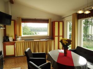 ein Wohnzimmer mit einem Tisch, Stühlen und einem Fenster in der Unterkunft Ferienhäuser Seewiesen in Reimershagen